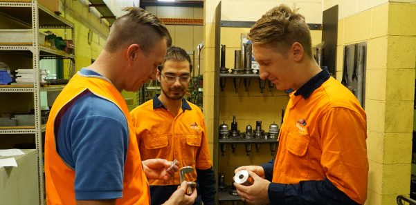 Sevaan Group - Engineering training Colleagues wearing orange uniform holding the steel metal parts products